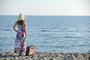 kvinna med resväska på de strand foto