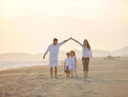 Lycklig ung familj ha roligt på strand på solnedgång foto