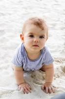 liten bebis flicka spelar med sand på strand. sensorisk utveckling för barn utomhus. foto