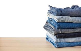 denim blå jeans stack på trä tabell isolerat på vit bakgrund foto