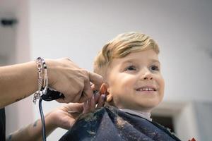liten pojke få en frisyr på frisörsalong. foto
