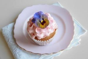 hemlagad rosa frosting vaniljmuffin med ätliga blommor foto