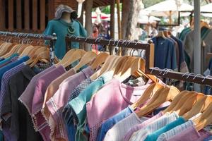 kläder kuggstänger med blå och lila bomull klänningar på galgar. monter med kläder på lokal- gata marknadsföra. foto