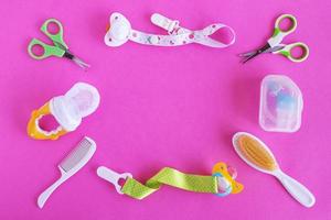 platt lägga på bebis vård objekt - sax, hårborstar, nappar, napp hållare, nasal aspirator och nappare- på rosa bakgrund med kopia Plats. begrepp av medicin och hygien av de barn. foto