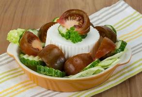 grekisk sallad i en skål på trä- bakgrund foto