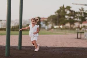 en liten flicka i modern sommar kläder spelar i de parkera i sommar. selektiv fokus foto