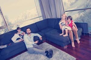 Lycklig ung familj spelar tillsammans på soffa foto