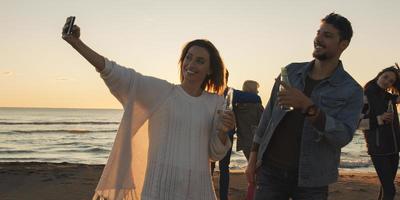 grupp av vänner har roligt på strand under höst dag foto