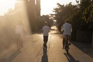 Lycklig familj njuter en skön morgon- tillsammans, föräldrar ridning en cykel och deras son ridning ett elektrisk skoter. selektiv fokus foto