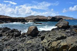 vågor kraschar mot lava sten i aruba foto