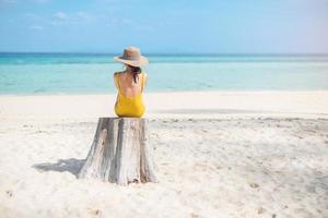 kvinna turist i gul baddräkt och hatt, ensamresenär som ser vacker havsutsikt på bambuön på phi phi don island, krabi, thailand. destination, sommarresor, semester och semesterkoncept foto