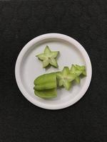 grön stjärna frukt skivor på en rosa plast tallrik foto