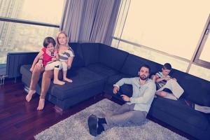 Lycklig ung familj spelar tillsammans på soffa foto