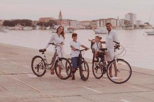 de Lycklig familj åtnjuter en skön morgon- förbi de hav ridning en cykel tillsammans och utgifterna tid tillsammans. de begrepp av en Lycklig familj foto