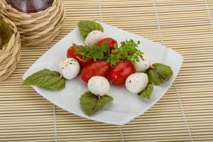 caprese sallad på tallriken och trä bakgrund foto