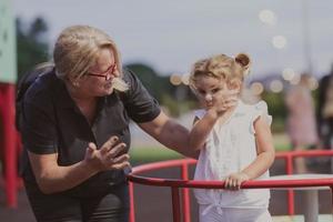 ett äldre mormor är spelar med henne barnbarn i de parkera på solnedgång. selektiv fokus foto