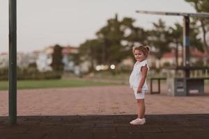 en liten flicka i modern sommar kläder står i de parkera i sommar. selektiv fokusu foto