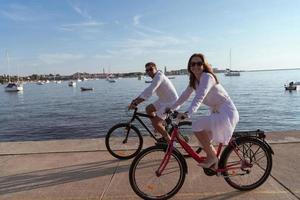 senior par njuter en skön morgon- tillsammans ridning en cykel förbi de hav. selektiv fokus foto
