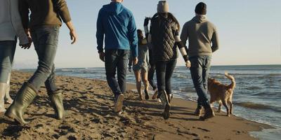 grupp av vänner har roligt på strand under höst dag foto