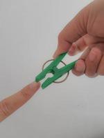 en hand försöker till nypa hans tumme använder sig av en grön klädnypa. foto