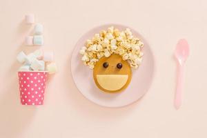bebis pannkakor för frukost. kreativ aning för de unge efterrätt utsökt pannkakor i de form av de Lycklig ansikte med de hår framställning popcorn foto