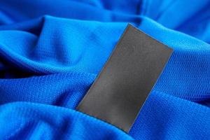 svart tom tvätt vård kläder märka på blå jersey polyester sport skjorta bakgrund foto