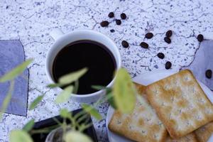 de varm svart kaffe i en vit kopp och de crackers är intensiv och gå väl tillsammans. foto