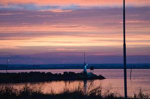 solnedgång i Sverige på de hamn av sjö vaettern. fyr i de bakgrund foto