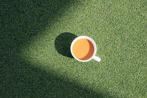 en varm kopp av kaffe på en kall morgon, på grön gräs med dagg bakgrund foto