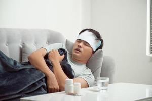 sjuk förlorad man liggande i soffa lidande kall och vinter- influensa virus har medicin tabletter i hälsa vård begrepp ser temperatur på termometer foto