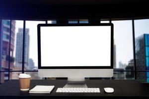 främre se arbetsyta med dator, smartphone och läsplatta på vit skrivbord med suddig bakgrund på kontor foto
