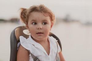 en porträtt av en leende liten flicka Sammanträde i en cykel sittplats. selektiv fokus foto