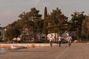 Lycklig familj njuter en skön morgon- förbi de hav tillsammans, föräldrar ridning en cykel och deras son ridning ett elektrisk skoter. selektiv fokus foto