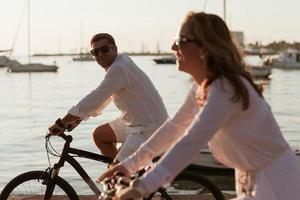 senior par njuter en skön morgon- tillsammans ridning en cykel förbi de hav. selektiv fokus foto