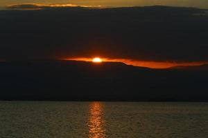 soluppgång på de Strand av de död- hav i israel. de Sol stiger från Bakom de bergen i jordan. foto