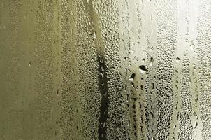 textur av en släppa av regn på en glas våt transparent bakgrund. tonad i gul Färg foto