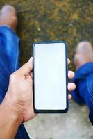 pOV skott av ung man hand använder sig av smart telefon med vit skärm foto