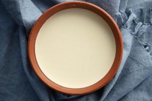 färsk yoghurt i en stor skål och en trasa på tabell foto