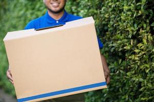 paketleverans man av ett paket genom en tjänst skicka hem. sända hand inlämnande kund accepterar en leverans av lådor från leveransman. foto