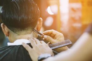 person man frisyr få eleganta hår årgång rakning, , med rakapparat förbi barberare frisör med händer på frisör. foto