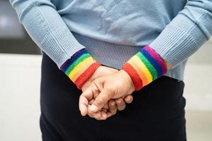 asiatisk dam som bär regnbågsflaggarmband, symbol för HBT stolthet månad firar årliga i juni sociala av homosexuella, lesbiska, bisexuella, transpersoner, mänskliga rättigheter. foto