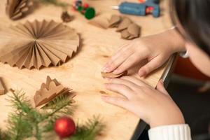 flicka gör jul träd dekorationer ut av papper med henne egen händer. steg 3. steg för steg instruktion foto