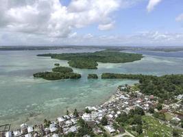 antenn se av by nära skön strand med små ö i de bakgrund i maluku, indonesien foto