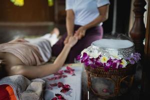 spa massage blommor dekorationer medan massös behandling av kontor syndrom traditionell thai massage stil. kvinna massös håller på med massage behandla hand, ärm smärta och påfrestning för kontor kvinna trött. foto