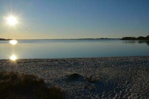 en sjö eller flod med brun gräs och Strand foto