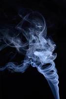 en vertikal skott av blå tobak rök på en svart bakgrund foto