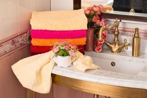 en närbild skott av vikta färgrik bambu handdukar på en badrum skåp med en bukett dekoration foto