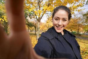 Lycklig ung kvinna tar selfie Foto i parkera med höst färger