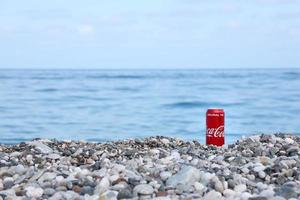 antalya, Kalkon - Maj 18, 2021 original- coca cola röd tenn kan lögner på små runda sten stenar stänga till hav Strand. Coca Cola på turkiska strand foto