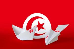 tunisien flagga avbildad på papper origami flygplan och båt. handgjort konst begrepp foto